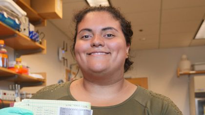 Person smiling with lab notebook